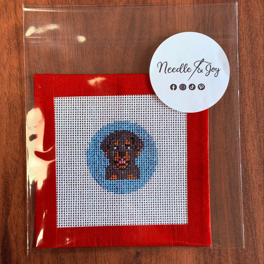 Needlepoint design on White Monocanvas fabric with a 'Needle to Joy' label.  Blue circle background  approx 1.5 inches